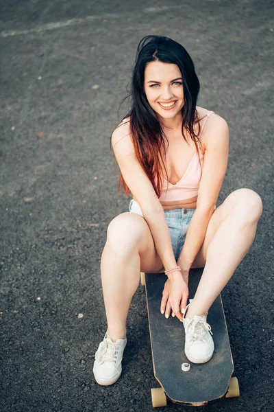 Skateboarder meisje glimlachend. Hipster meisje zit op skateboard — Stockfoto