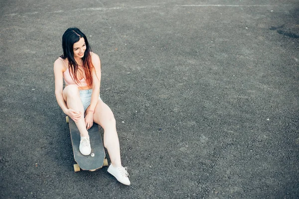 Skateboarder meisje glimlachend. Hipster meisje zit op skateboard — Stockfoto