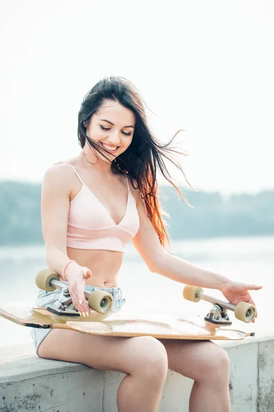 Mujer rubia casual en camisa de mezclilla posando en escaleras con longboard — Foto de Stock