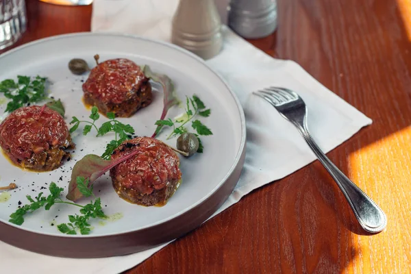 Taş bir plaka üzerinde bir yumurta ile biftek tartar. Kiraz domates. Rosemary. Baharat.