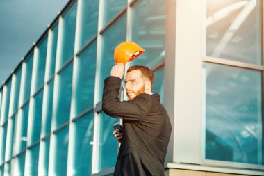 Oluşturucu mühendis kask giyer veya inşaat arka plan üzerinde elinde tut