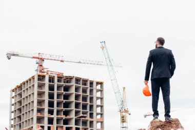 Erkek müteahhit ya da inşaat mühendisi inşaat projesine bakıyor