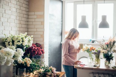 Ofiste oturup kahve fincanı ile güzel düşünceli işkadını çiçekçi