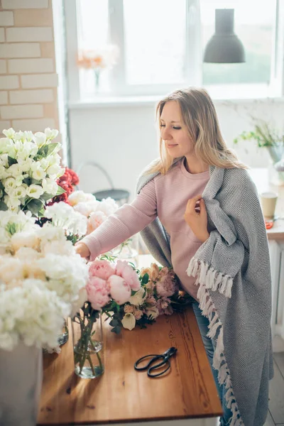 Усміхаючись мила молода жінка флорист організовує рослини в квітковому магазині — стокове фото