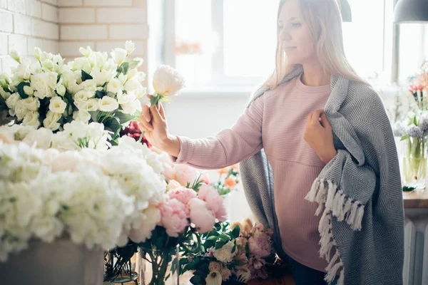 Sonriente encantadora florista joven que arregla las plantas en la tienda de flores — Foto de Stock