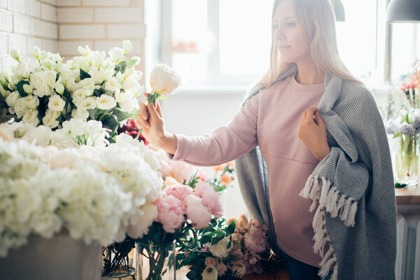Smiling lovely young woman florist arranging plants in flower shop