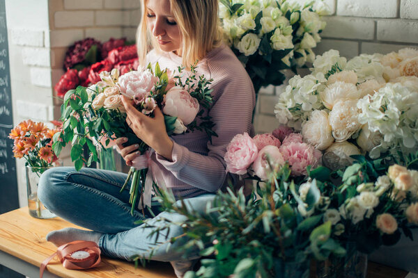 Portrait of young female florist with red tulips looking at camera