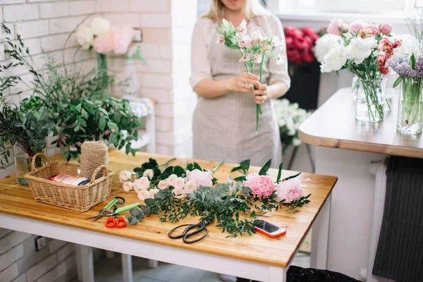 Sonriente encantadora florista joven que arregla las plantas en la tienda de flores —  Fotos de Stock