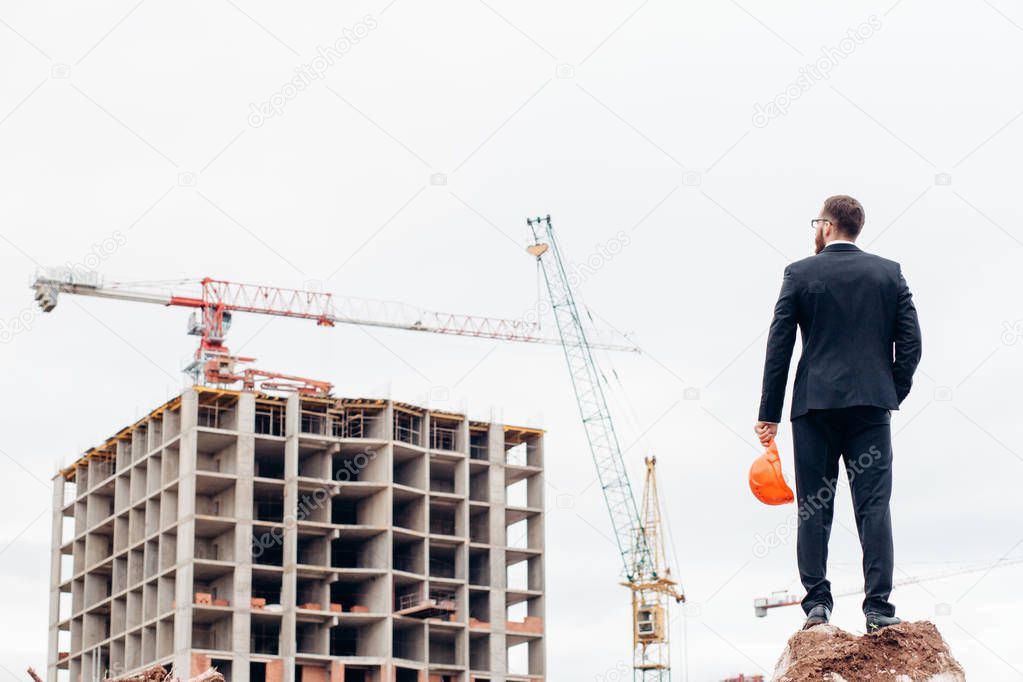 Male contractor or civil engineer looking at the building project on progress