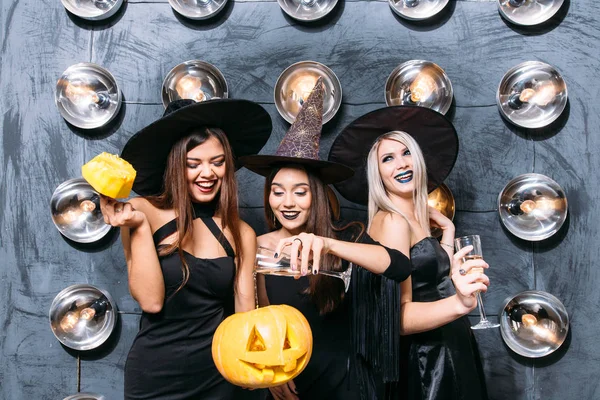 Tre giovani donne emotive in costume di Halloween sulla festa con zucca — Foto Stock
