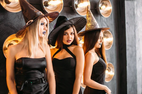 Három vidám fiatal nő boszorkány halloween jelmez sütőtökkel — Stock Fotó