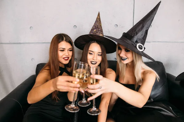Молодые люди позируют в шляпах на Хэллоуин и с шампанским — стоковое фото