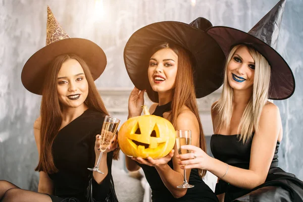Хэллоуинская вечеринка. три девушки пьют шампанское и садятся на кровать — стоковое фото