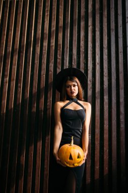 Güzel genç kadın cadı şapka ve kabak tutan kostüm.