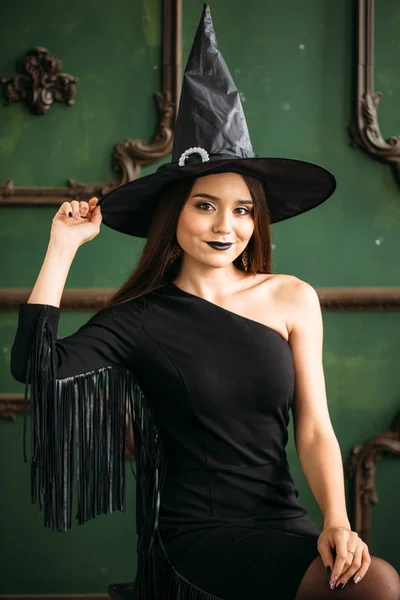 Mulher bonita em traje de bruxa preta com chapéu — Fotografia de Stock