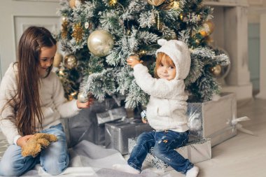İki kız Noel Baba Noel ağacın önünde döşeme şapka