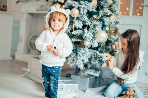İki kız Noel Baba Noel ağacın önünde döşeme şapka
