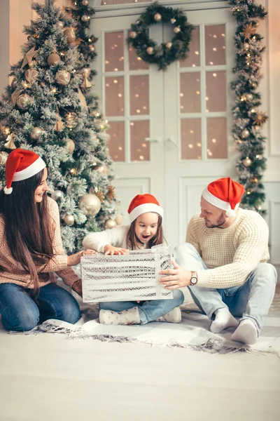 Förvånad över liten flicka med julklappar nära en julgran hemma — Stockfoto