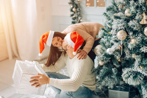 Pareja feliz en Santa Sombrero con regalo de Navidad y Año Nuevo en casa — Foto de Stock
