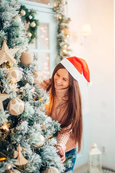 Noel balosunu Noel ağacının önünde tutan mutlu genç kadın — Stok fotoğraf