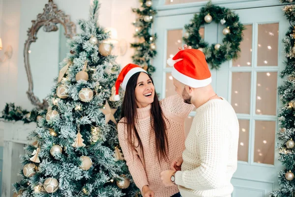Εικόνα που δείχνει νεαρό ζευγάρι να αγκαλιάζεται πάνω από χριστουγεννιάτικο δέντρο — Φωτογραφία Αρχείου
