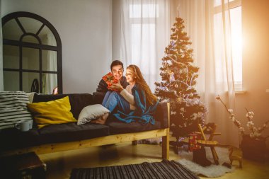 kadın açık hediye kutusu ve onun erkek arkadaşı ona yakın koltukta oturan süre gülümseyen