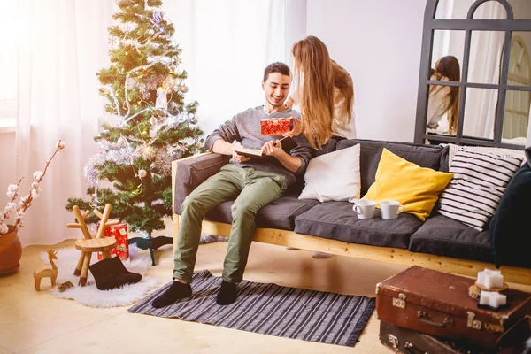 Krásná dívka dává její přítel dárek u vánočního stromu — Stock fotografie