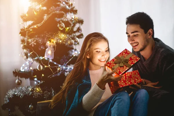 Ung kvinna med man tittar på julklapp — Stockfoto