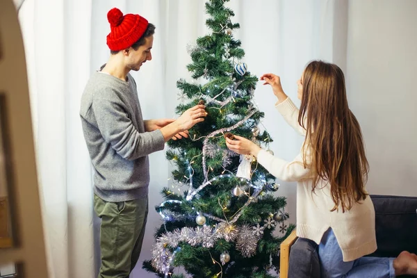 Pareja feliz joven decorando un árbol de Navidad. Luz natural, enfoque selectivo — Foto de Stock