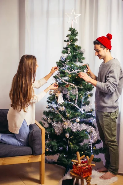 Linda pareja joven decorando un árbol de Navidad — Foto de Stock