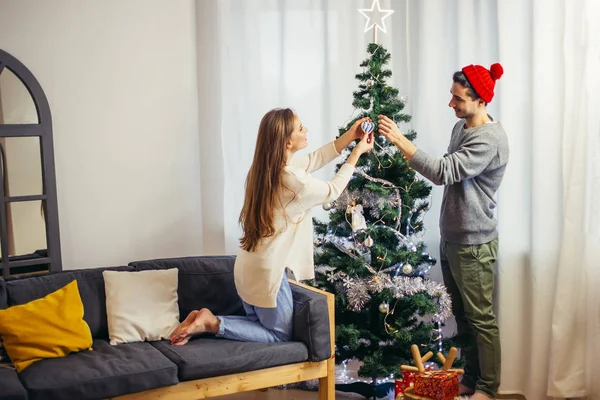 Linda pareja joven decorando un árbol de Navidad — Foto de Stock