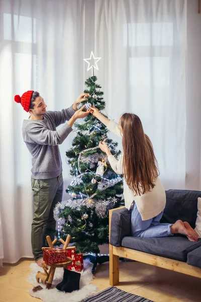 Mignon, jeune couple décorer un arbre de Noël — Photo