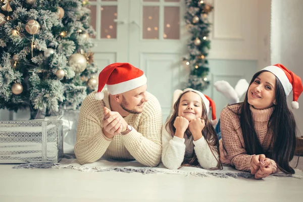 Οικογένεια με καπέλο Santa που βρίσκεται κοντά στο χριστουγεννιάτικο δέντρο, διακοπές γιορτή έννοια — Φωτογραφία Αρχείου