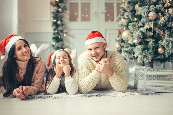 Οικογένεια με καπέλο Santa που βρίσκεται κοντά στο χριστουγεννιάτικο δέντρο, διακοπές γιορτή έννοια — Φωτογραφία Αρχείου