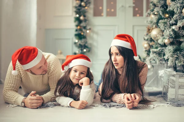 クリスマス ツリー、休日の祭典概念の近くに横たわってサンタ帽子と家族 — ストック写真