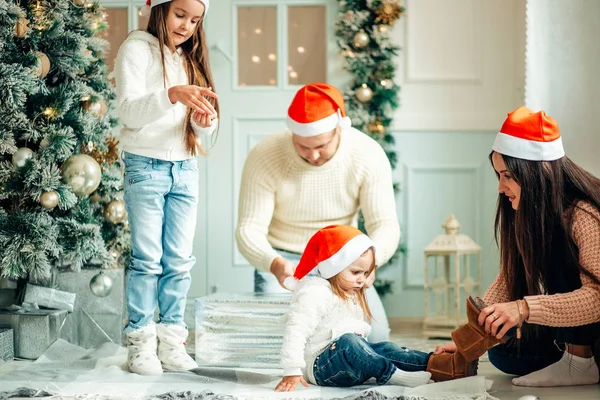 きれいに飾られたクリスマス ツリーの横に座っている美しい家族が帽子を着用します。 — ストック写真