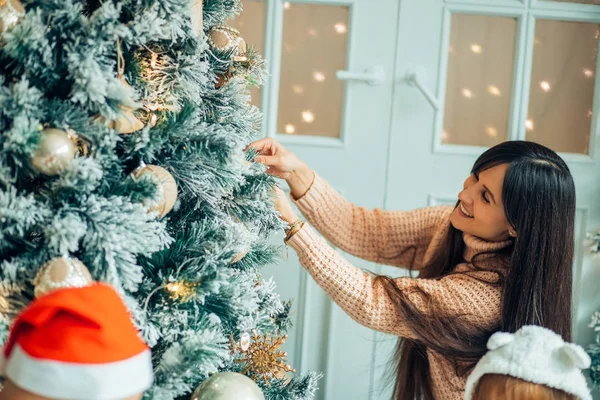 Sevimli kız ve annesi Noel arifesinde ilk ağacı süslüyorlar. — Stok fotoğraf