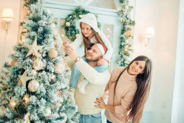Mutlu bir aile Noel ağacını bayraklarla süslüyor oturma odasında. — Stok fotoğraf