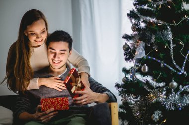 Young woman with husband looking at Christmas gift clipart