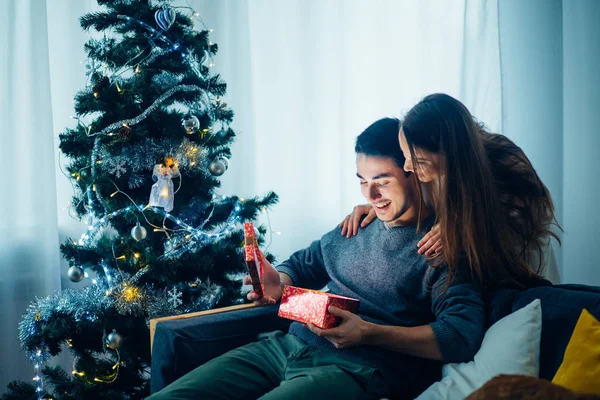 Mladá žena s manželem při pohledu na vánoční dárek — Stock fotografie