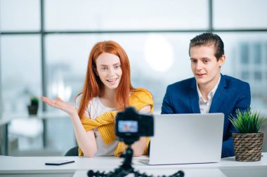 İki video blogcusu bir şey hakkında konuşuyor ve gülümsüyor.