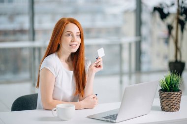 Kredi kartı tutan ve kameraya bakarak iş kadını