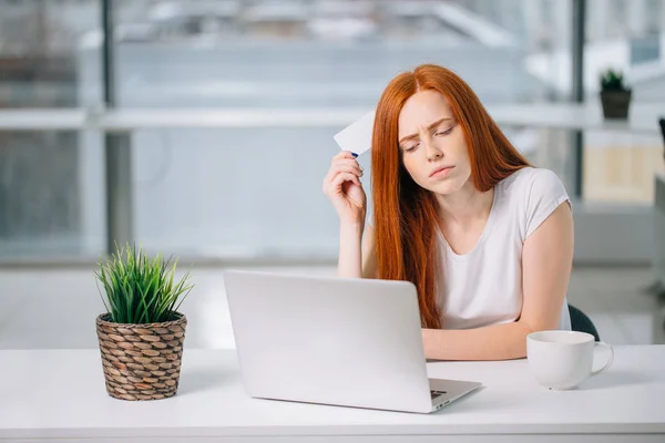 思考商务妇女坐在桌上与笔记本电脑, 持有空的信用卡 — 图库照片