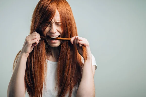 Üzgün kızıl kız yaralı saçlarını ısırıyor.. — Stok fotoğraf