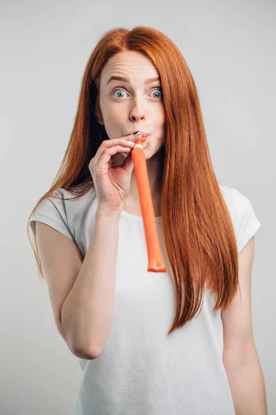 Funny lovely pinup girl blowing in party whistle and holding copyspace on palms — Stock Photo, Image