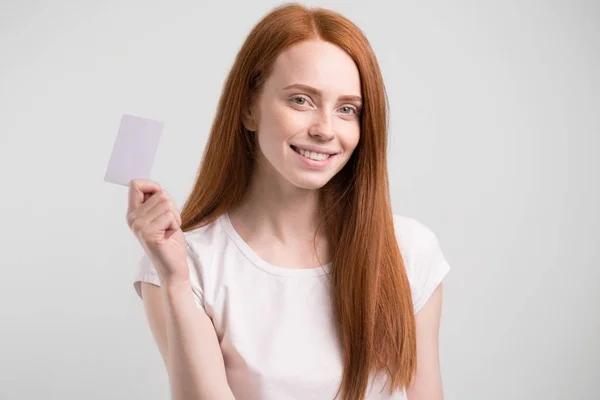 Kredi kartı tutan ve beyaz arka plan üzerinde gülümseyen Kızıl saçlı kız. — Stok fotoğraf