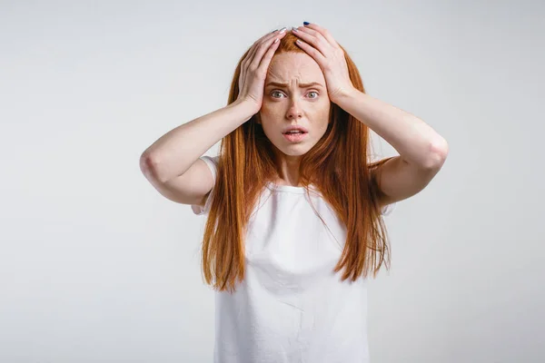 Redhead girl on white background with strong expression of fear, round eyes — Stock Photo, Image