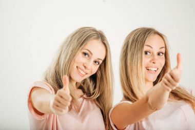 Başparmak yukarıya üstünde beyaz arka plan ile ikiz kardeşler