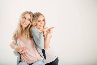 Beyaz arka plan üzerinde işaret eden iki neşeli attrative kız ikiz