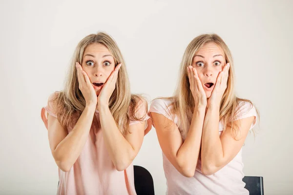 Überraschtes Mädchen, das ihren Schwester-Zwilling auf weißem Hintergrund betrachtet — Stockfoto